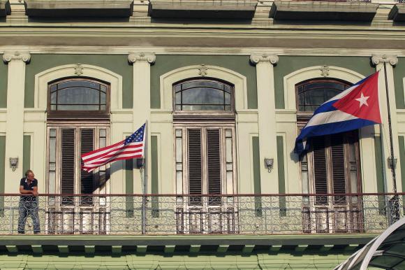Man stands near national flags of U.S. and Cuba on balcony of a hotel being used by first U.S. congressional delegation to Cuba since change of policy announced by U.S. President Obama, in Havana