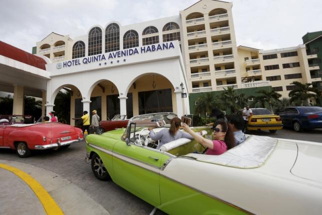Tourists take a selfie while sitting in a vintage car outside the Quinta Avenida Habana Hotel in Havana, March 19, 2016. REUTERS/Stringer