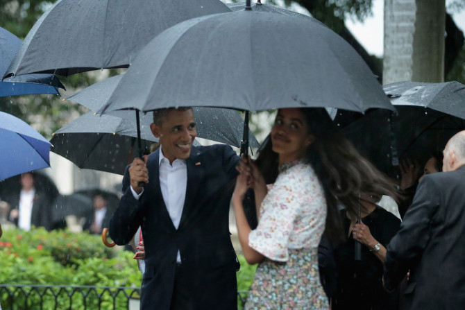 HAVANA, CUBA - MARCH 20:  Taking shelter from the pouring rain under umbrellas, U.S. President Barack Obama, his daughter Malia, 17, and members of the first family take a walking tour of in the plaza of the 18th century Catedral de San Cristobal de la Habana in the historic Old Havana neighborhood March 20, 2016 in Havana, Cuba. Obama is the first sitting president to visit Cuba in nearly 90 years.  (Photo by Chip Somodevilla/Getty Images)