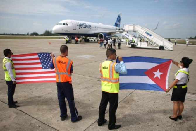 Ground crew hold U.S. and Cuban flags near a recently landed JetBlue aeroplane, the first commercial scheduled flight between the United States and Cuba in more than 50 years, at the Abel Santamaria International Airport in Santa Clara, Cuba, August 31, 2016. REUTERS/Alexandre Meneghini