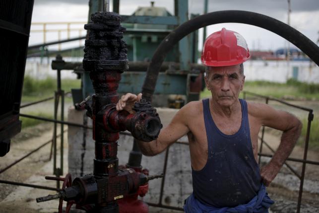 Alfredo, 69, a technician of Cuba's state-run CUPET, poses for a picture near an oil pump in Mayabeque province, Cuba, October 15, 2015.   REUTERS/Enrique de la Osa